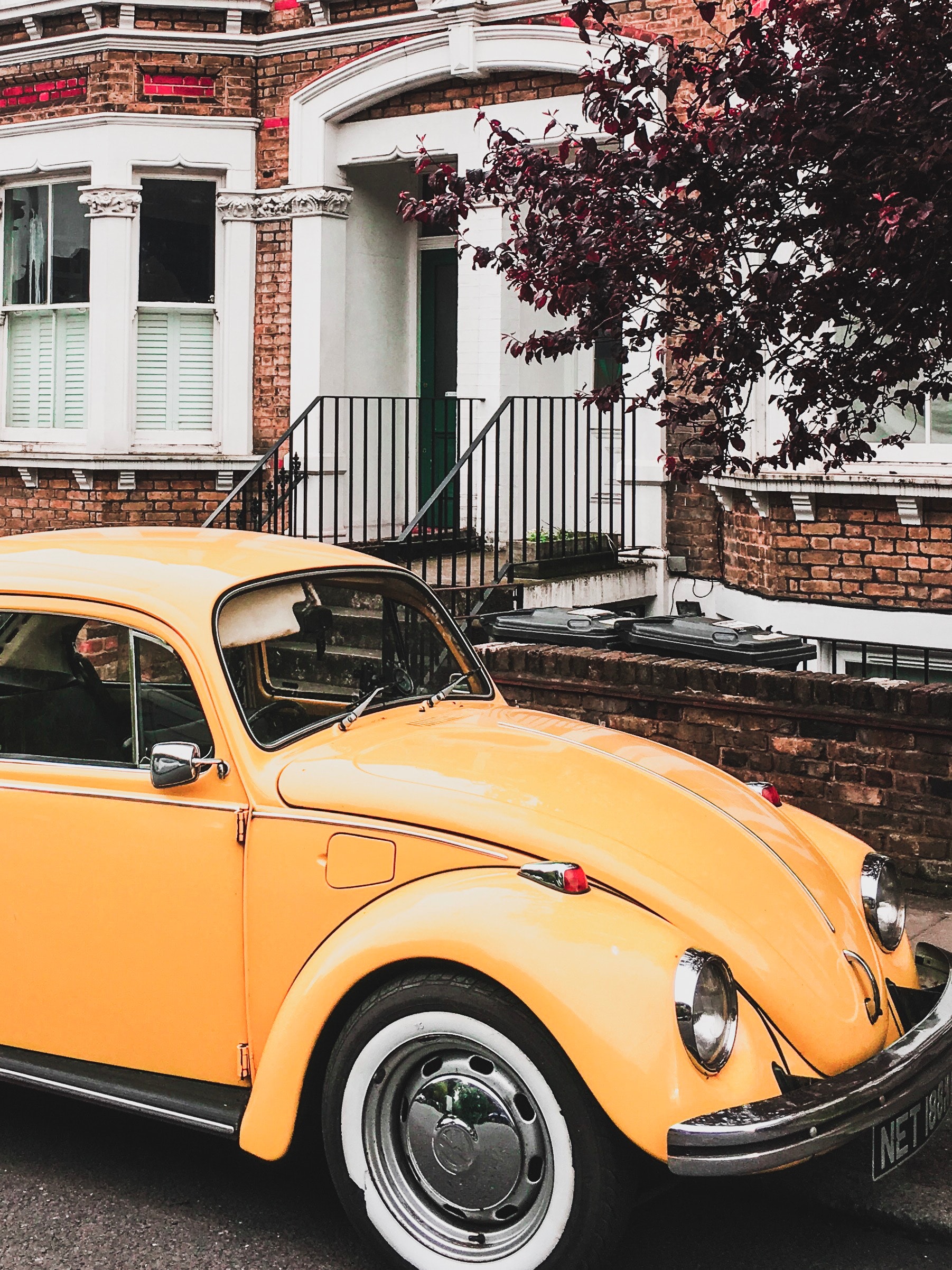 Yellow VW Beetle Parked by the Curb Next to a House